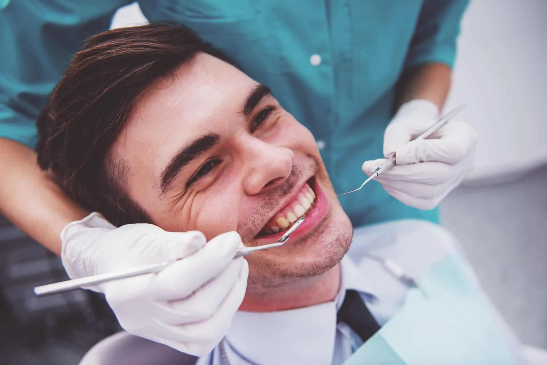 a man sitting in a chair with a dentist holding tools